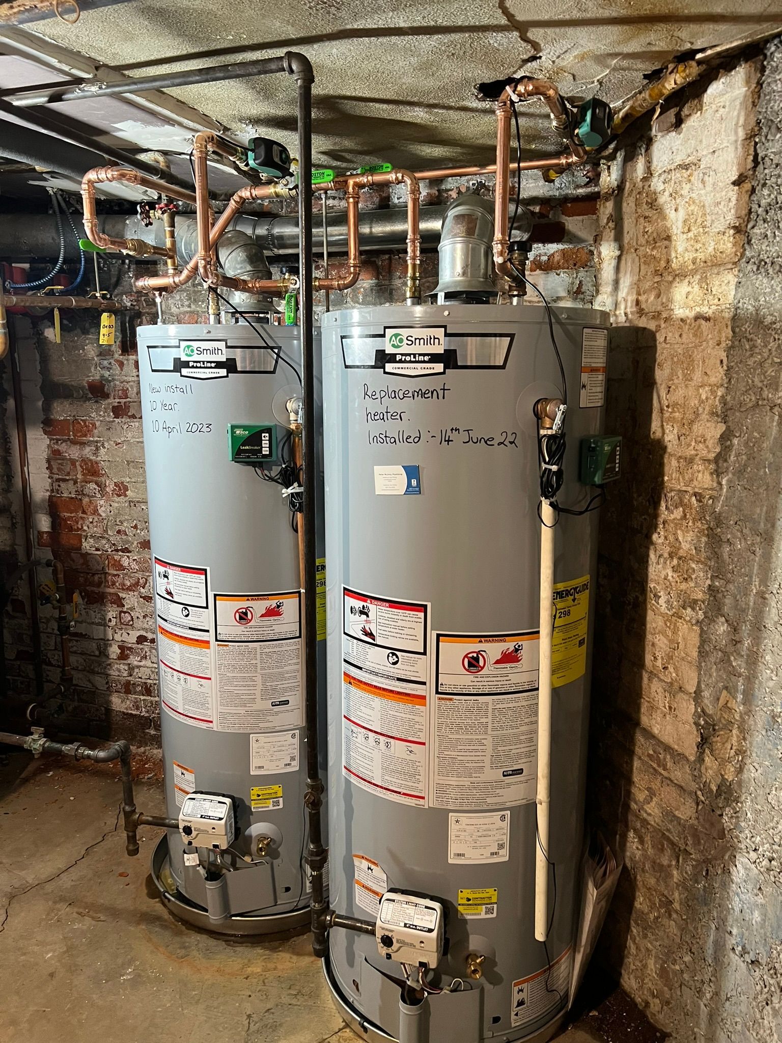two water heaters are sitting next to each other in a basement