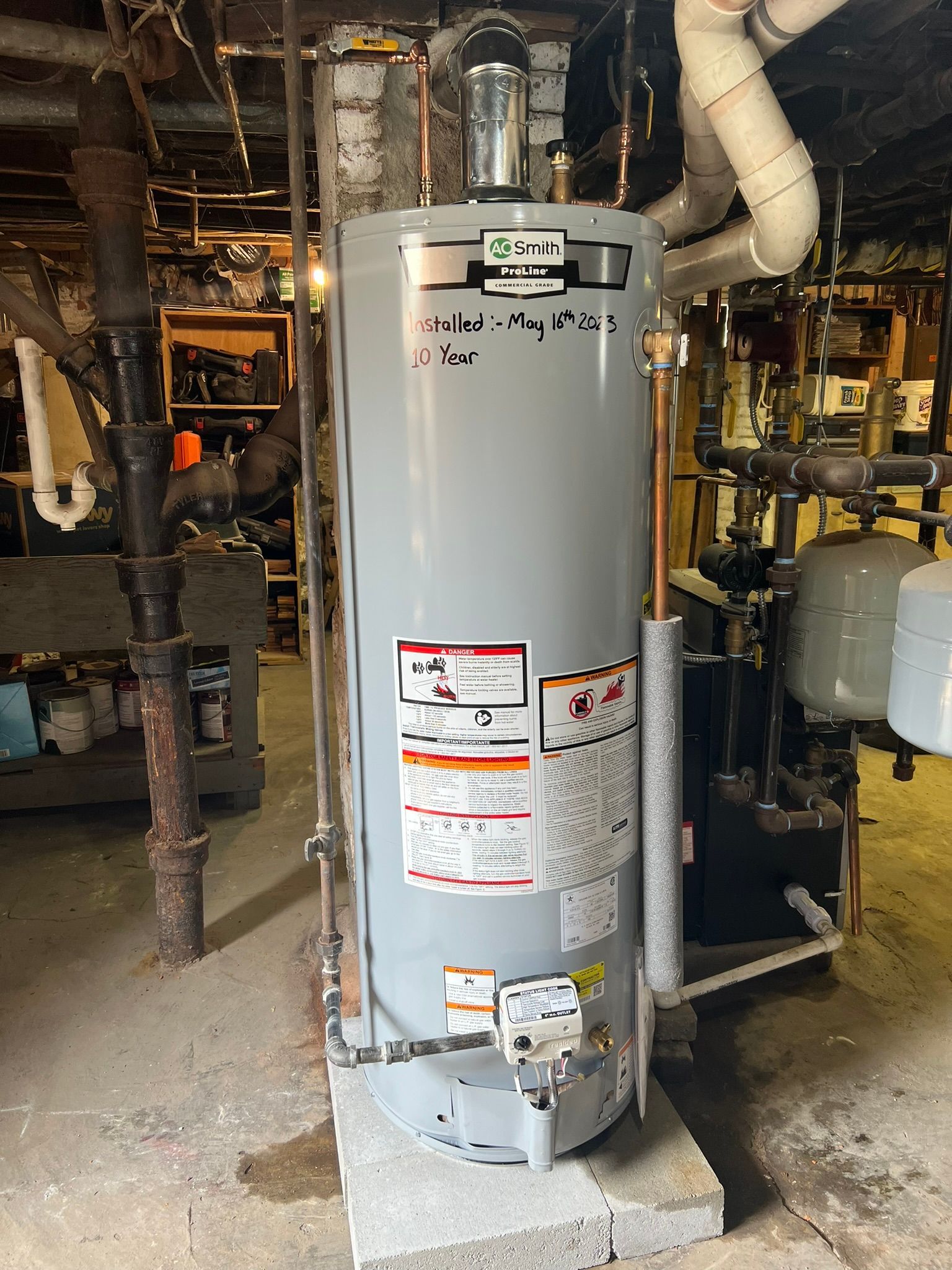 a water heater is sitting in a basement next to pipes