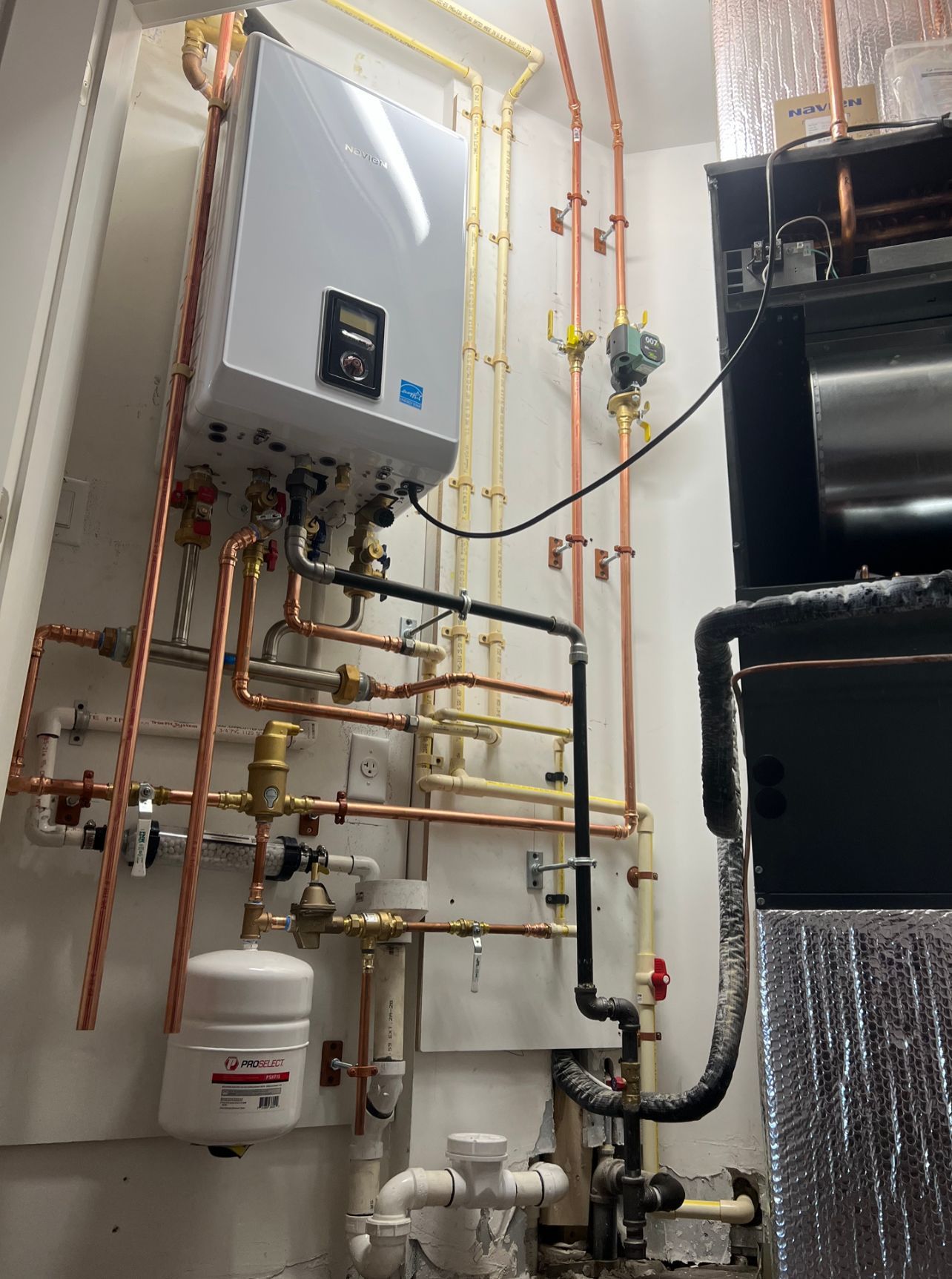 a room with a lot of pipes and a boiler on the wall