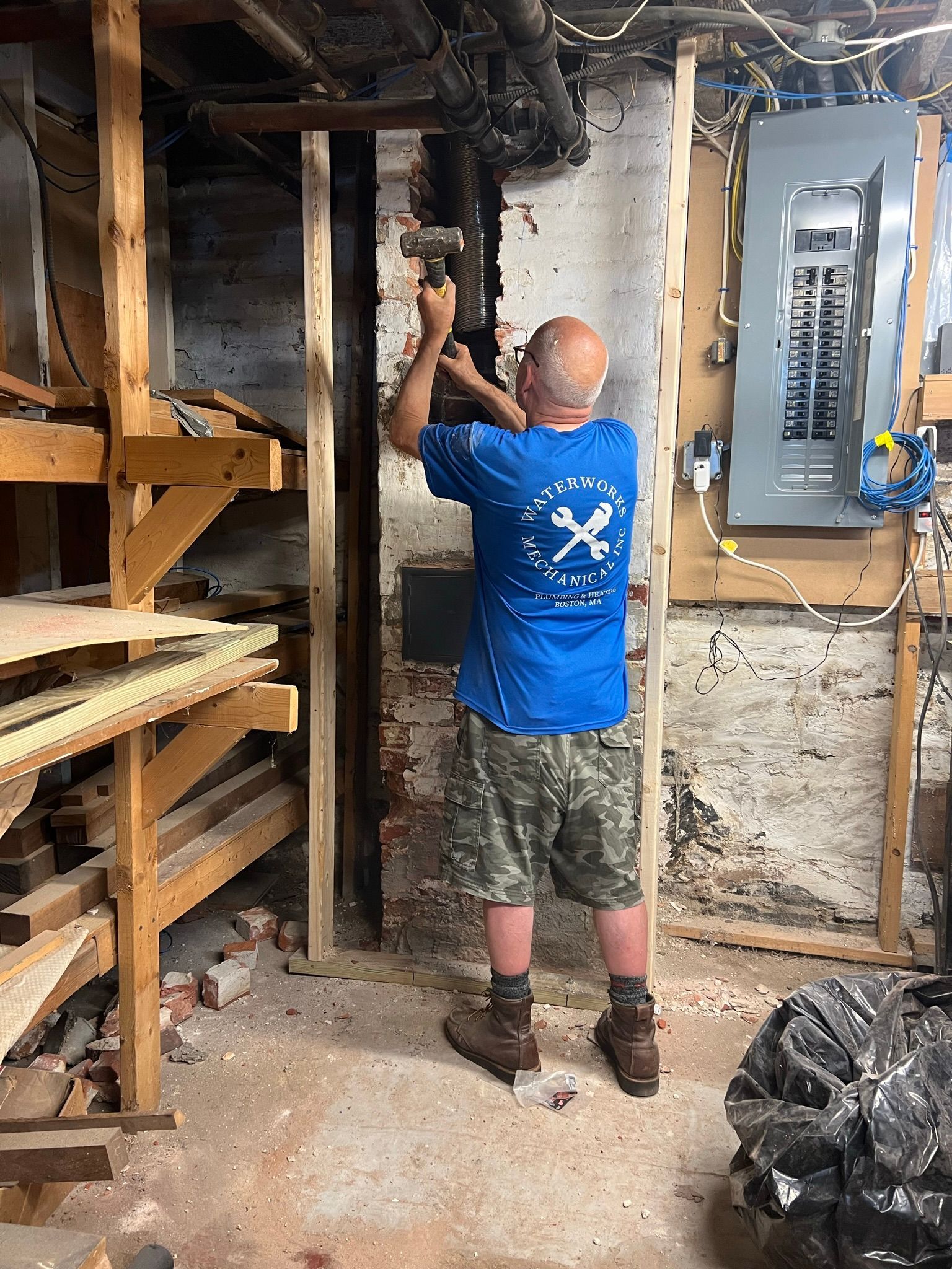 a man in a blue shirt is working on a pipe in a basement
