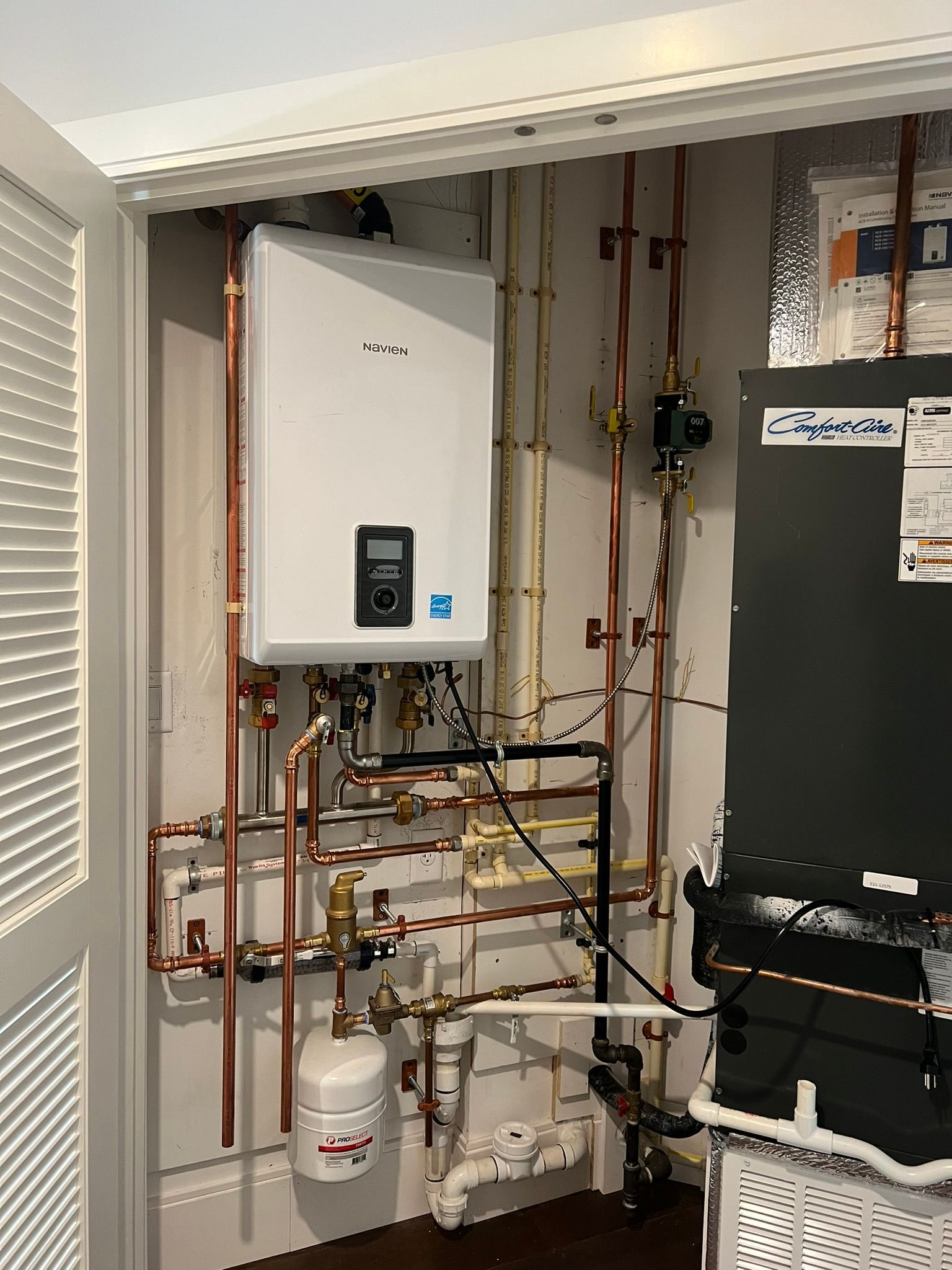 a white water heater is sitting in a room with copper pipes