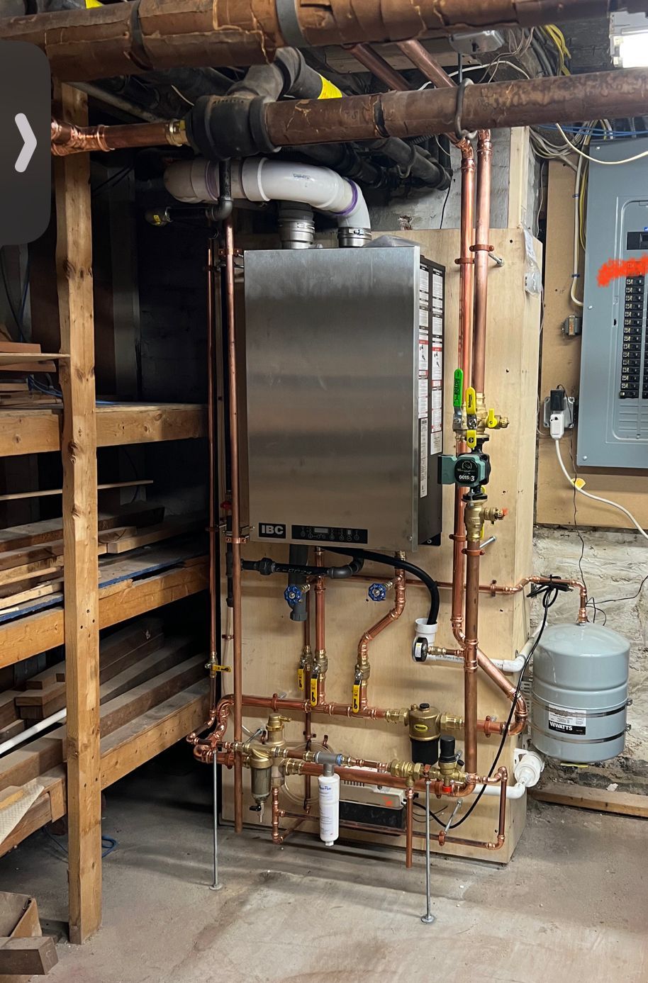 a stainless steel water heater is sitting in a basement next to copper pipes