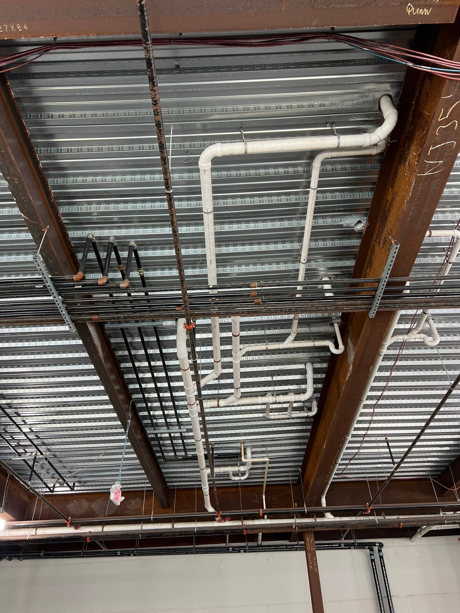 a ceiling with pipes and wires hanging from it