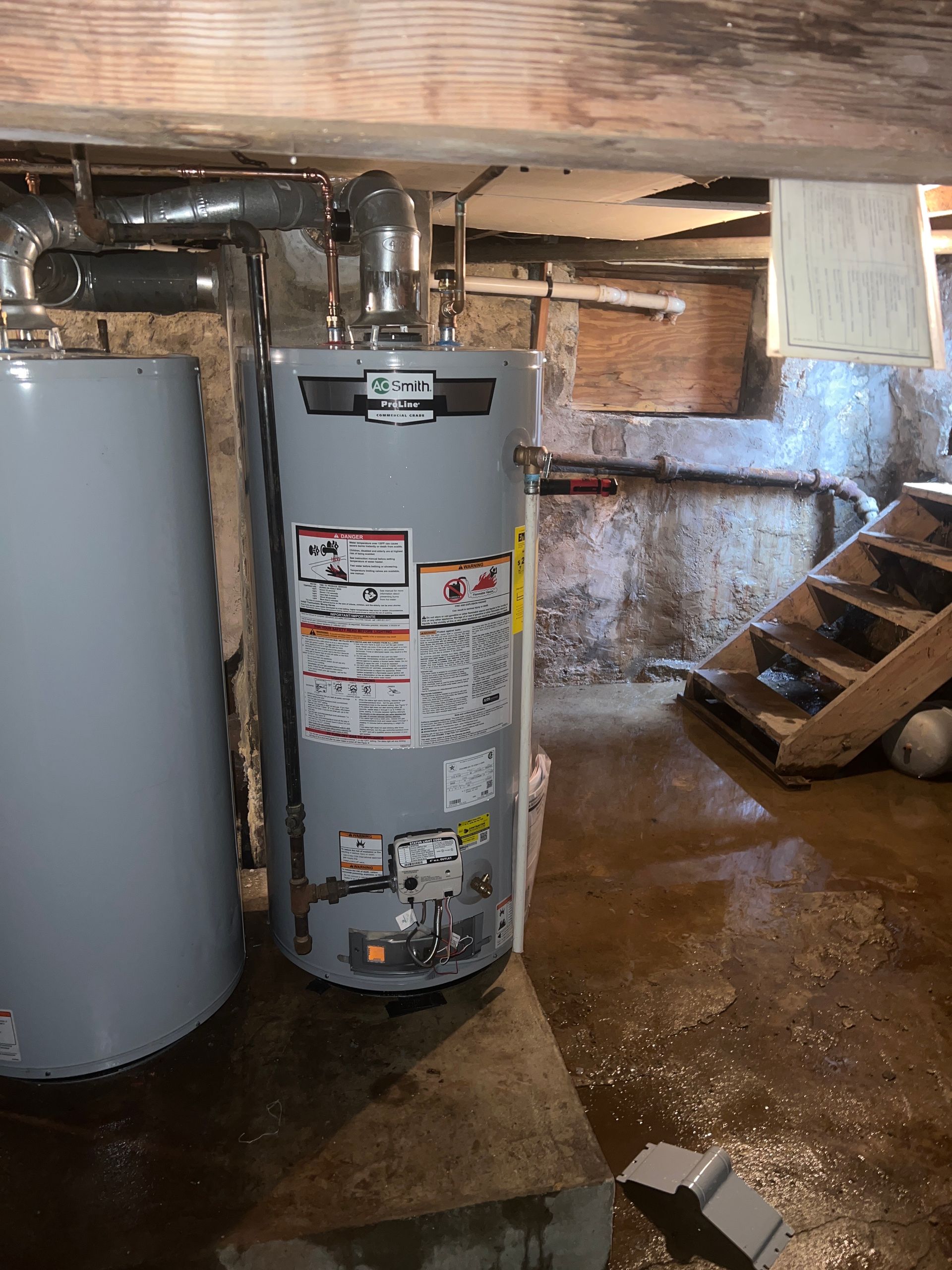 a water heater is sitting in a basement next to a staircase