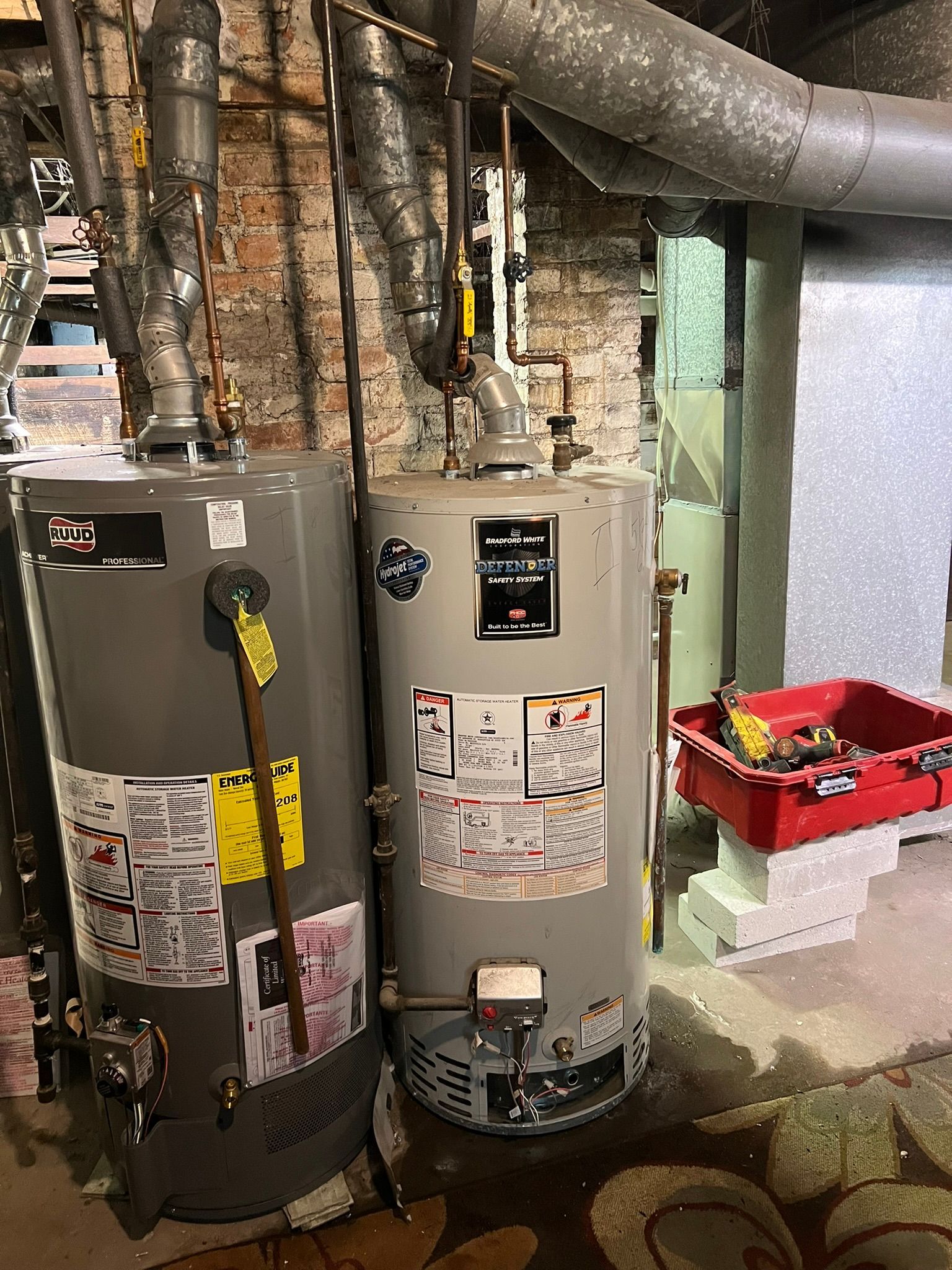 two water heaters are sitting next to each other in a basement