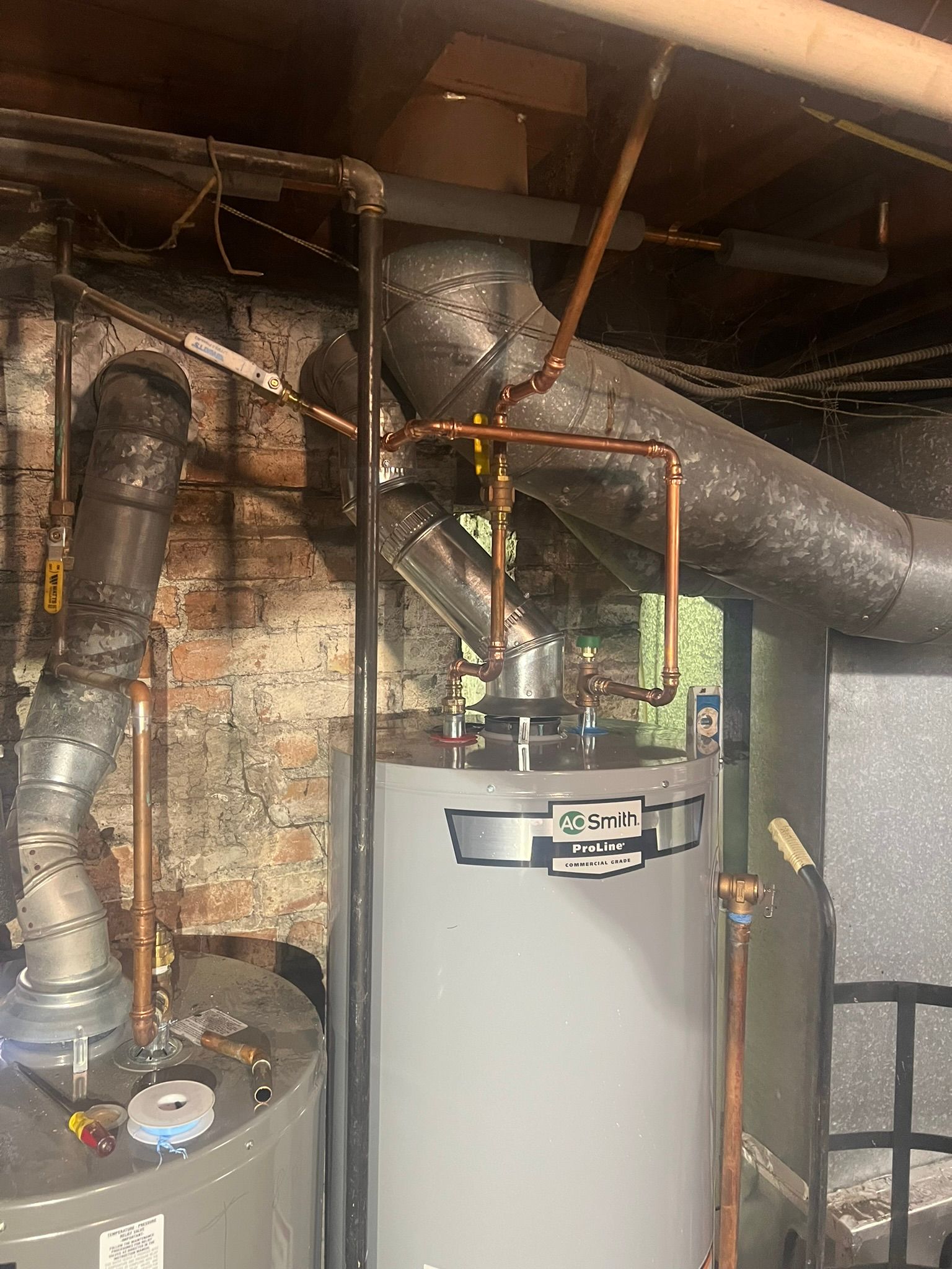 a water heater is sitting in a basement next to a brick wall