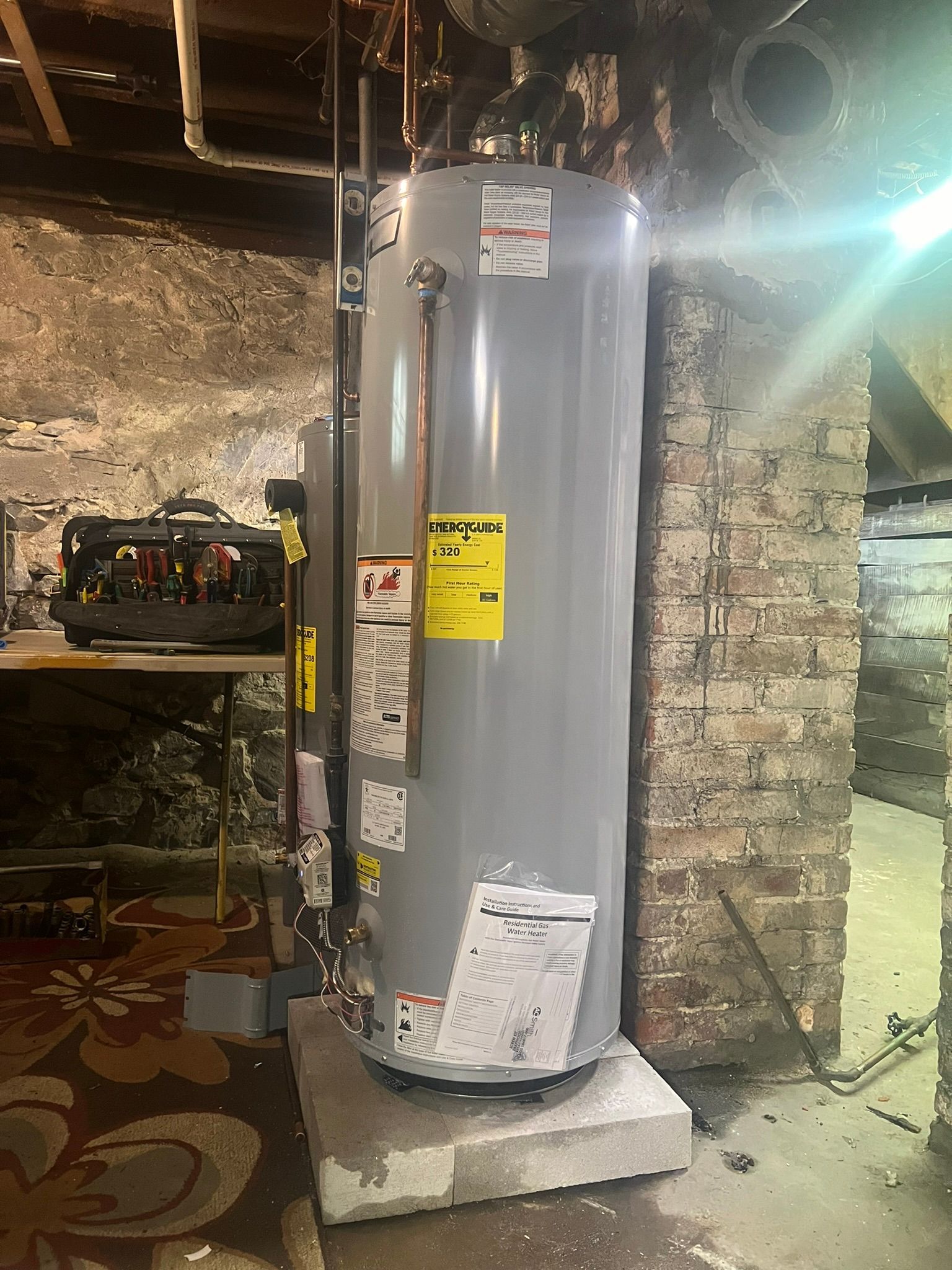 a water heater is sitting in a basement next to a brick wall