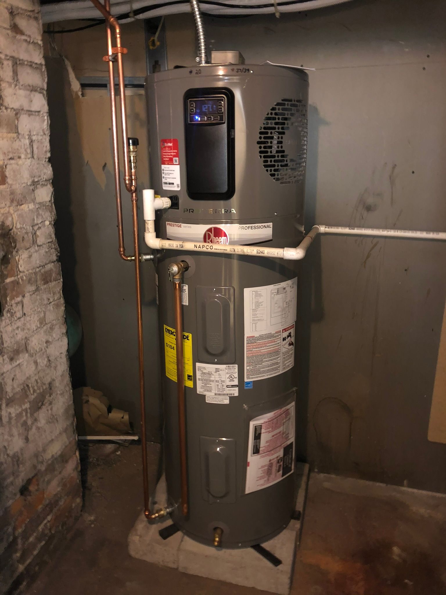 a water heater is sitting in a basement next to a brick wall