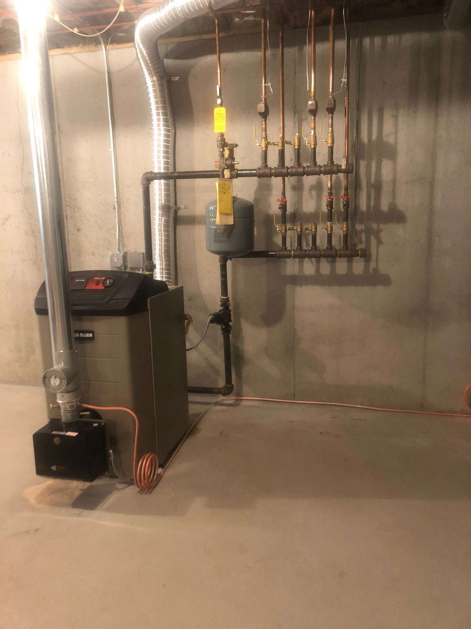 a boiler is sitting in a basement next to pipes