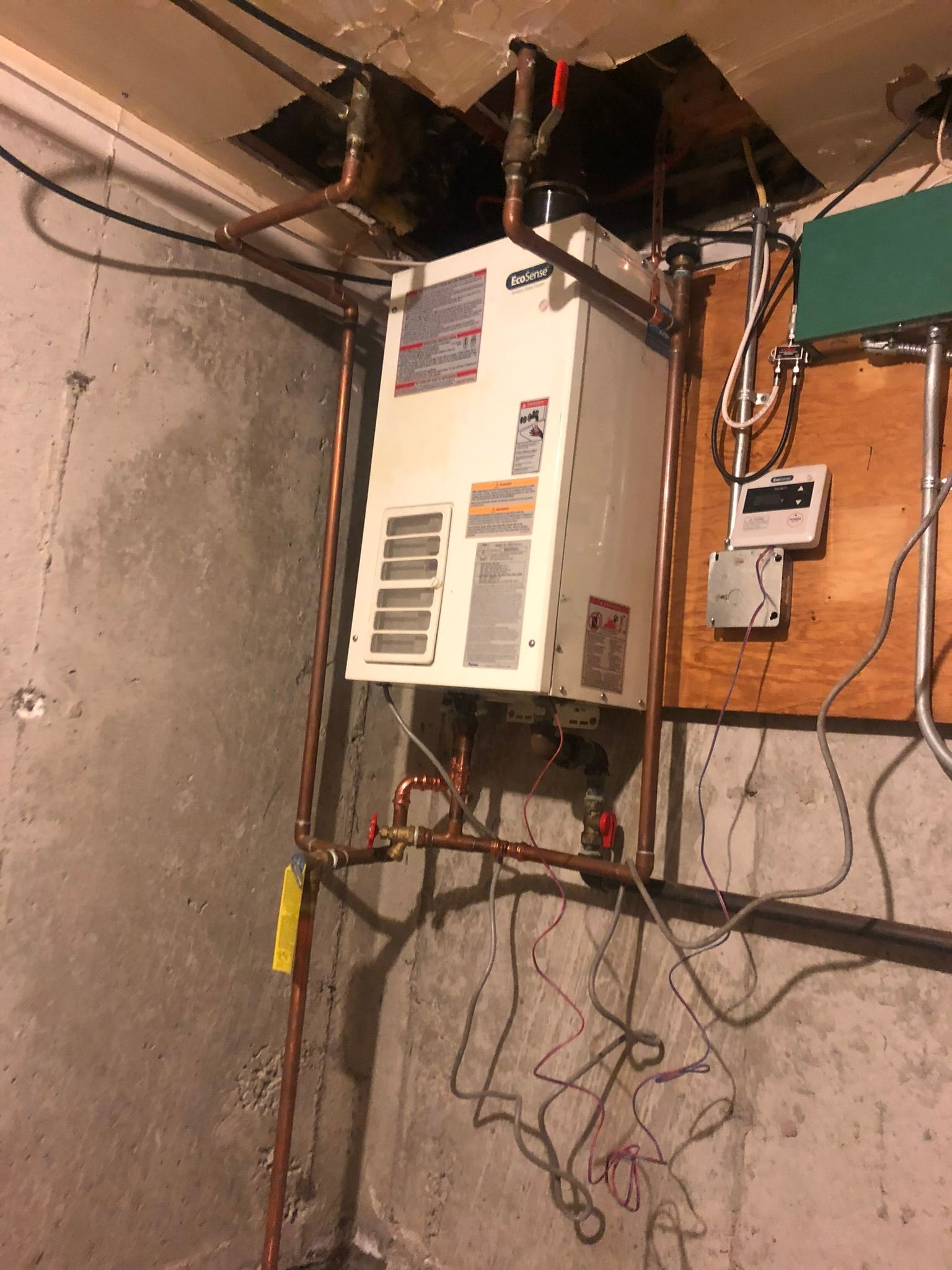 a water heater is hanging from the ceiling in a basement