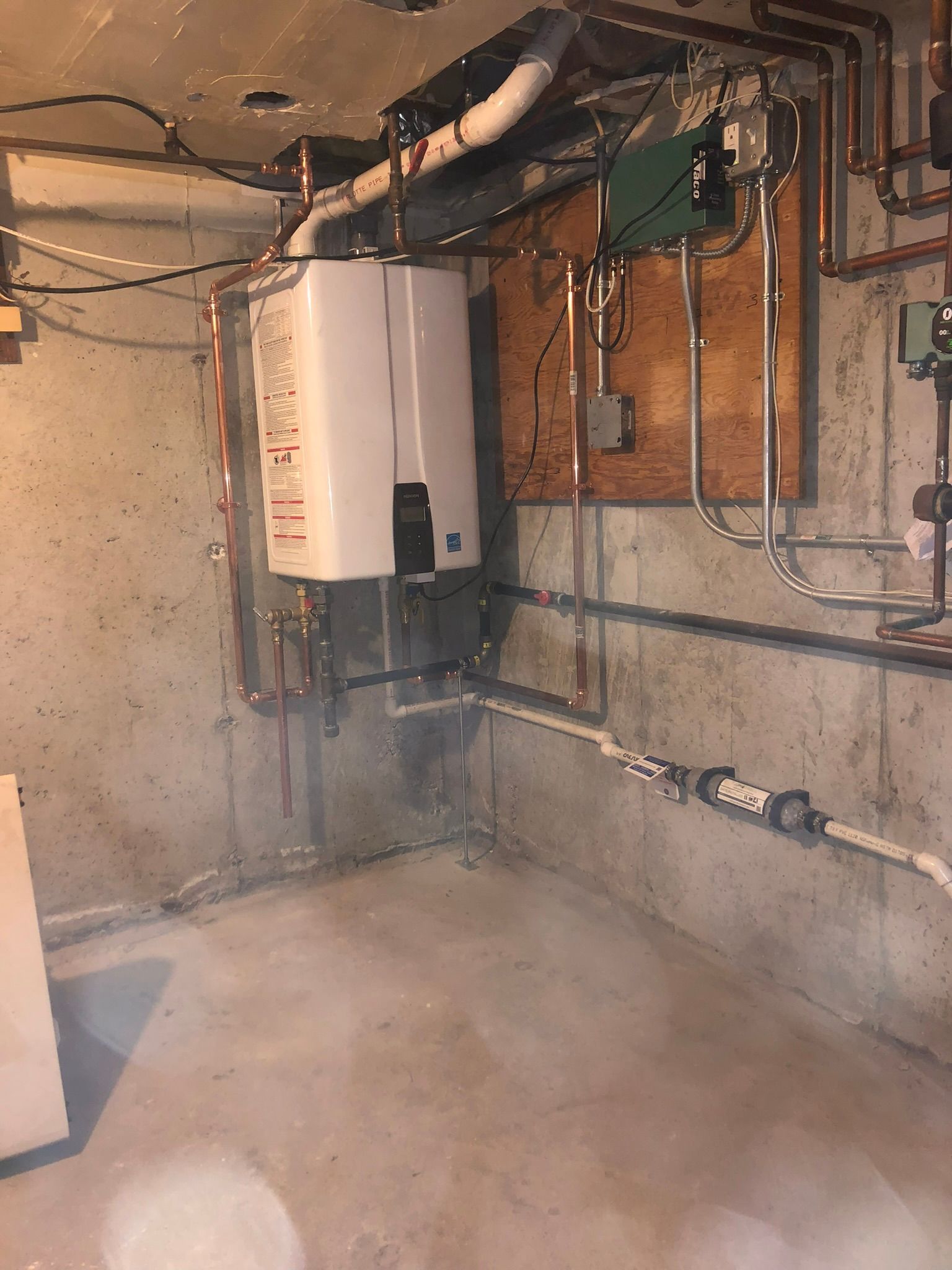 a room with a water heater and pipes hanging from the ceiling