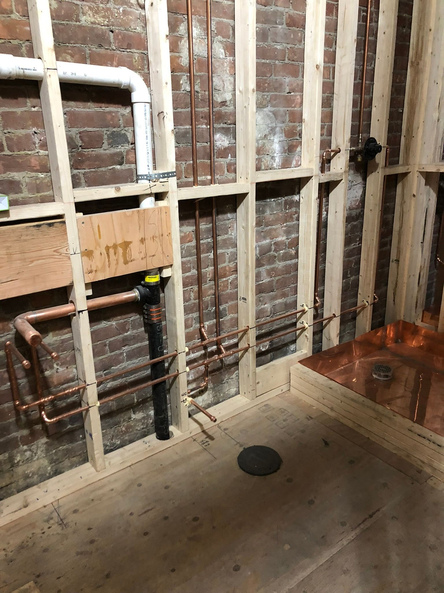 a room with a brick wall and copper pipes in it