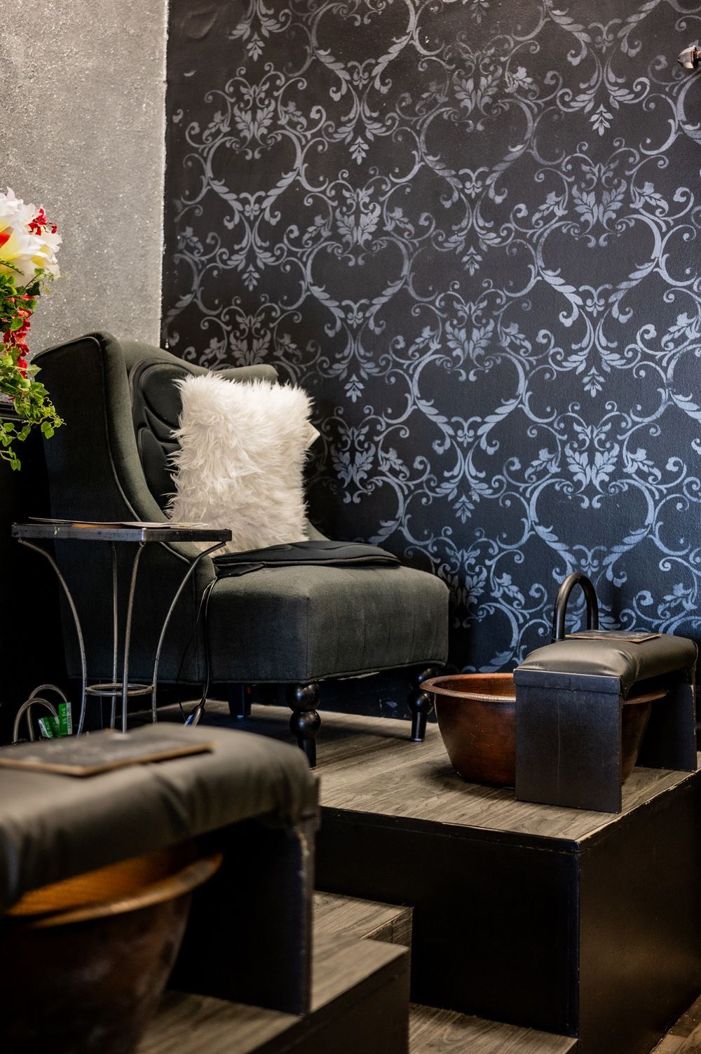 A chair and ottoman are in a room with a black wall.