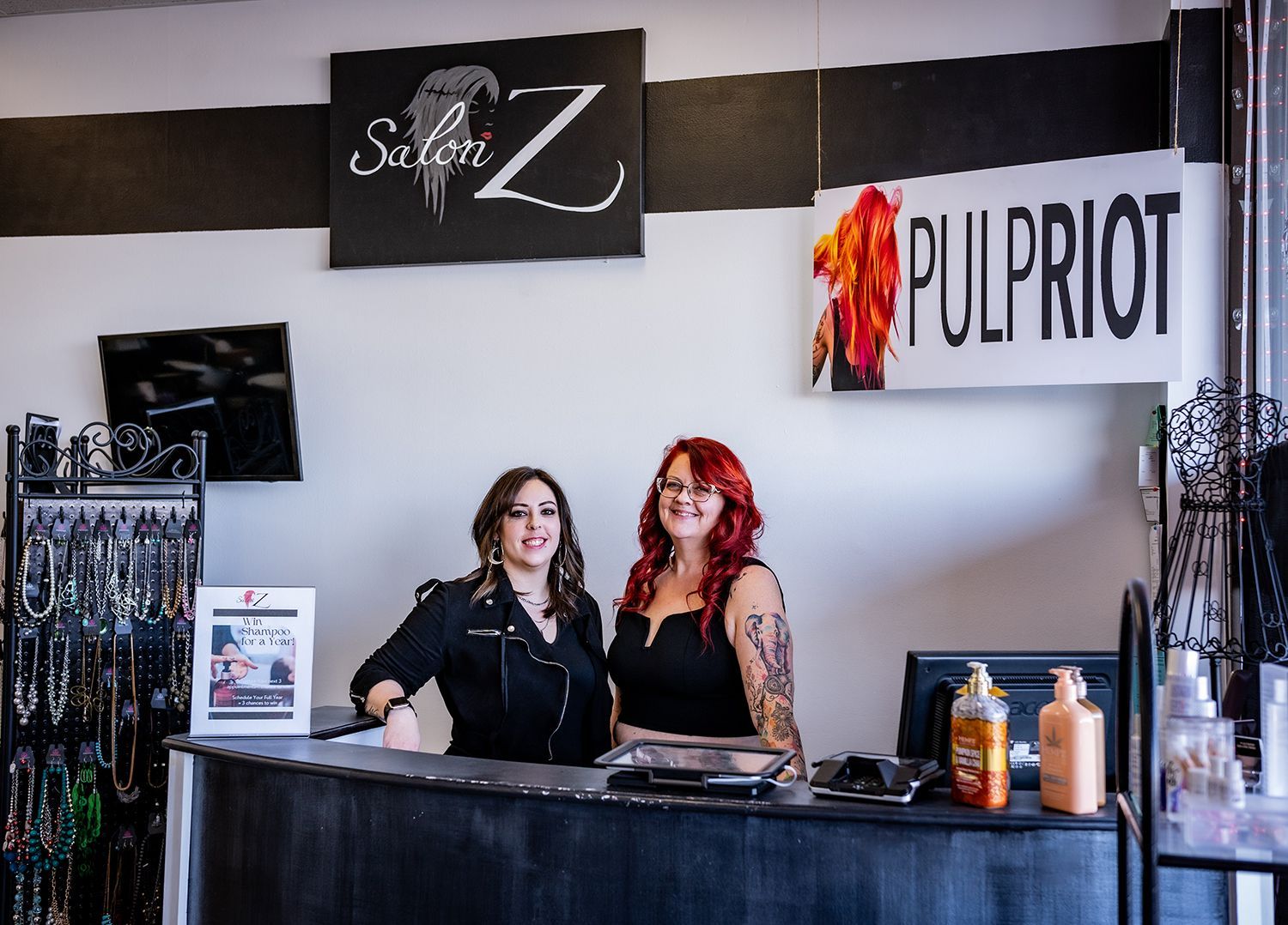 Two women are standing behind a counter in a salon.