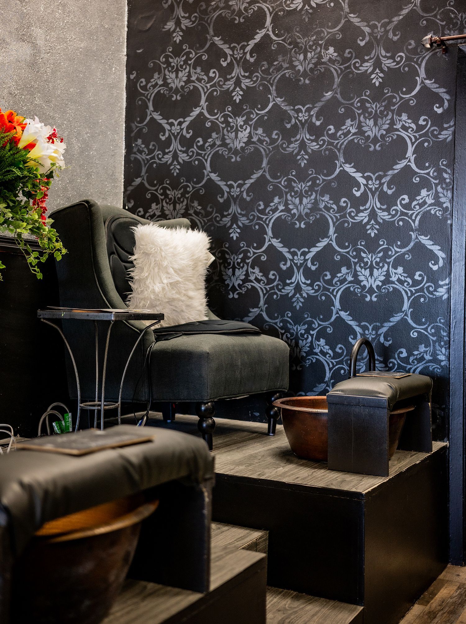 A chair and ottoman are in a room with a black wall.