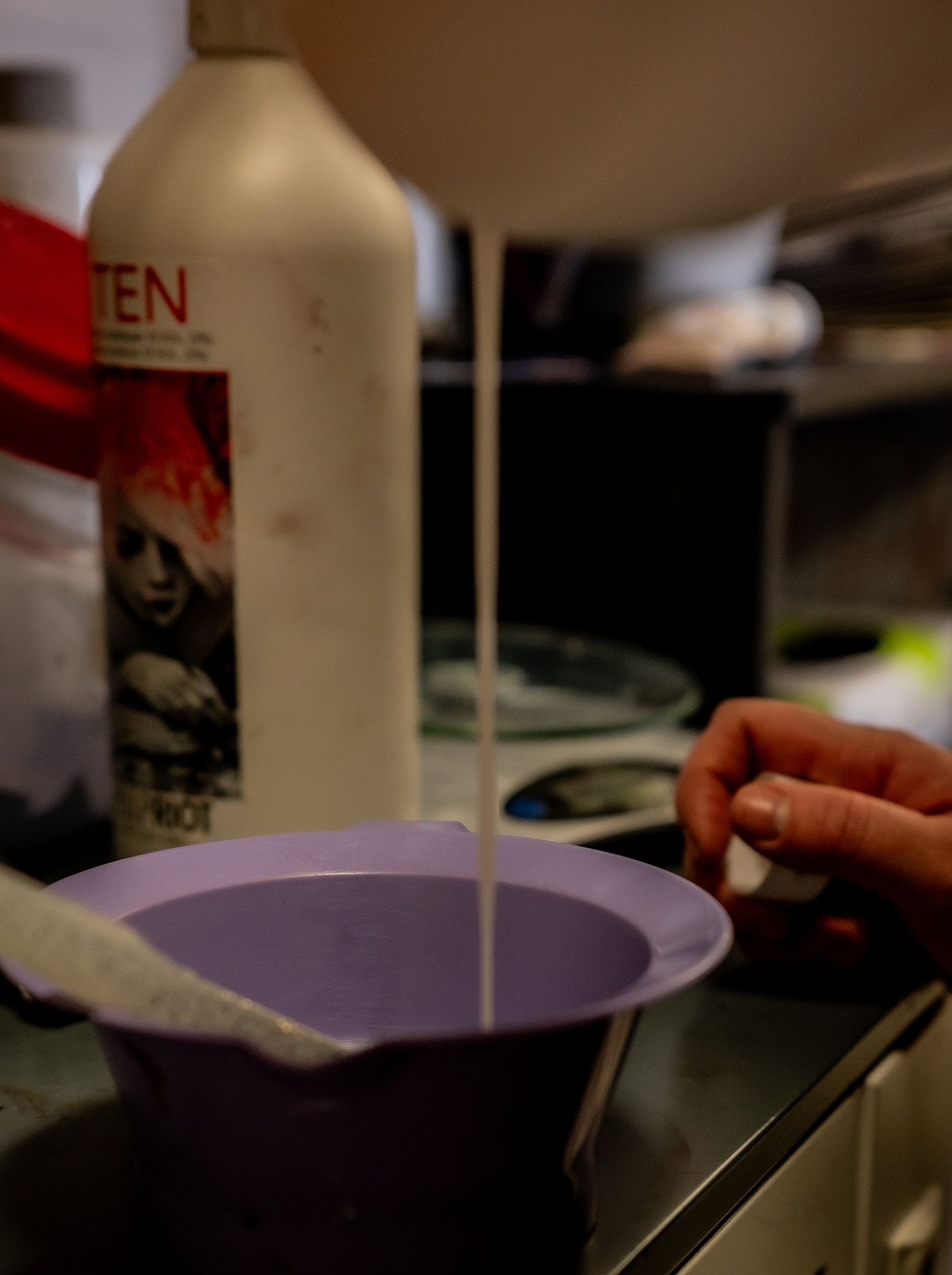 A bottle of ten is poured into a purple bowl