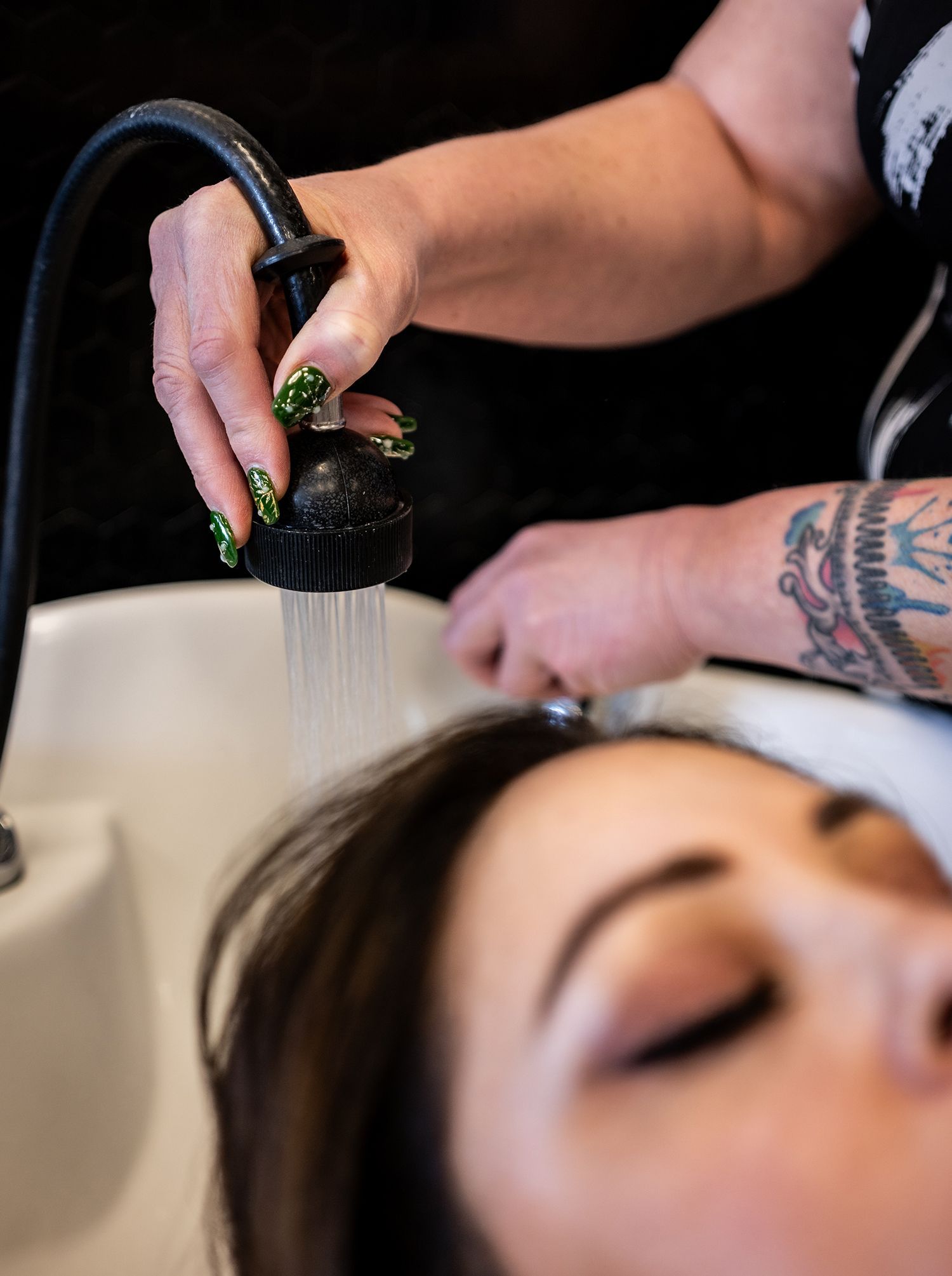 A woman is getting her hair washed in a sink by a hairdresser.