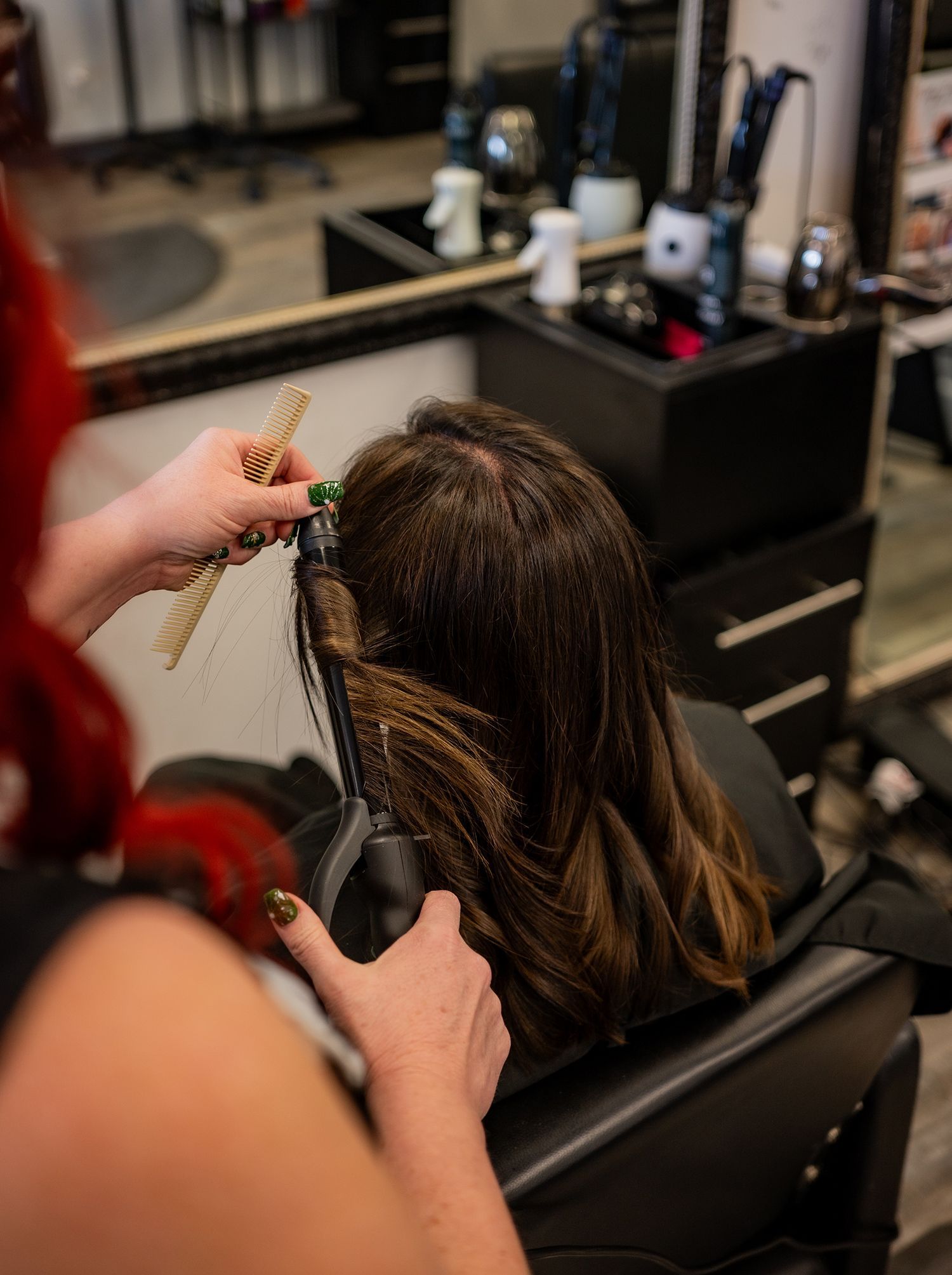 A woman is getting her hair done by a hairdresser in a salon.