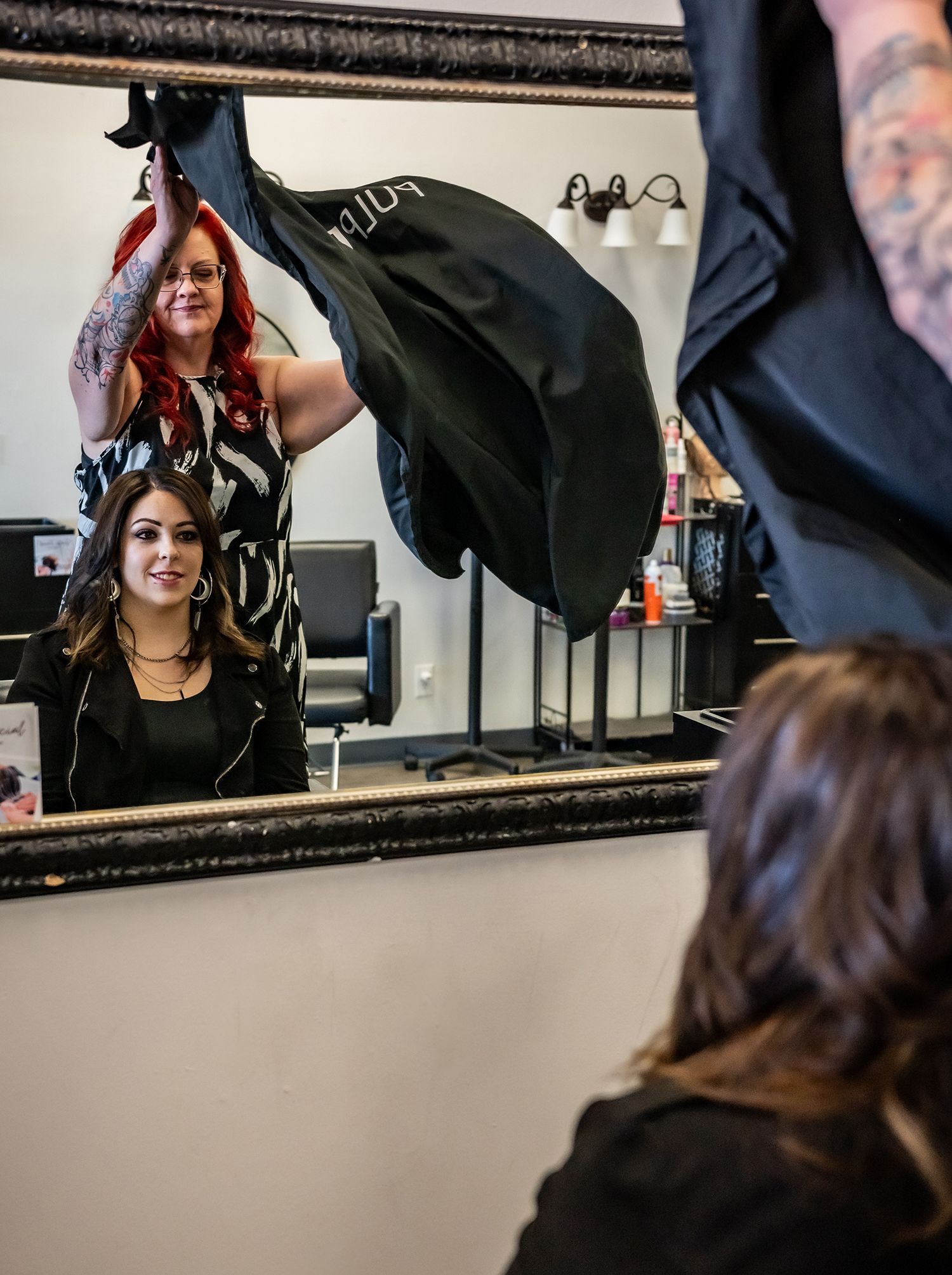 A woman with red hair is getting her hair cut by a hairdresser