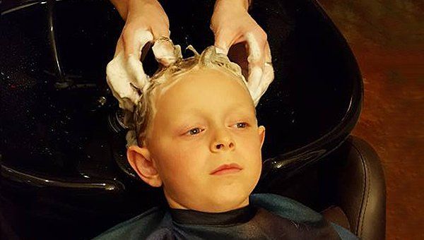 Boy getting his hair washed in a salon, soapy hair, black wash basin, hands in the hair.