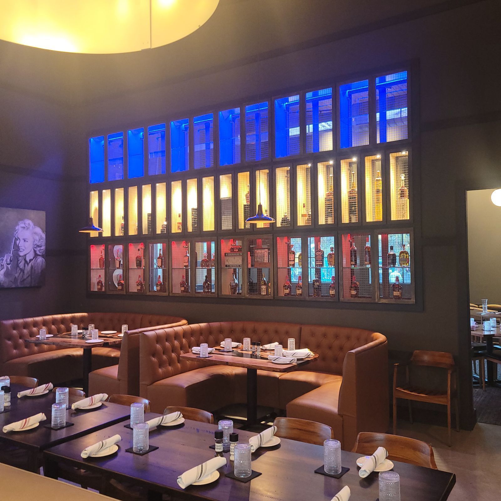 A restaurant with tables and chairs and a wall with bottles on it