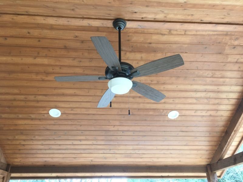 A ceiling fan is hanging from the ceiling of a wooden building.