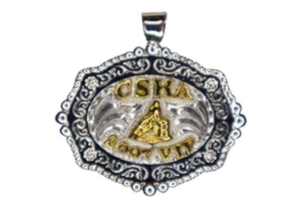 A silver and gold pendant with the word cska on it
