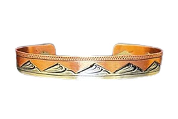 A copper bracelet with mountains on it on a white background.