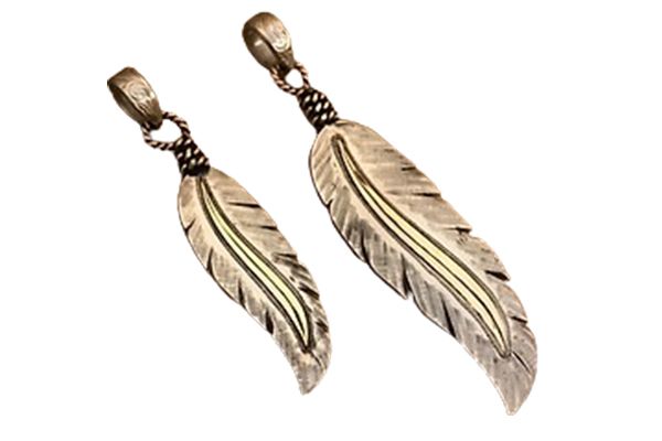 Two feather shaped pendants on a white background