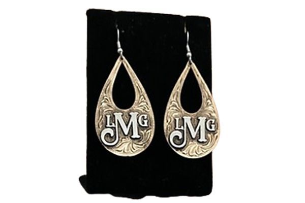 A pair of earrings with the letters lmg on them