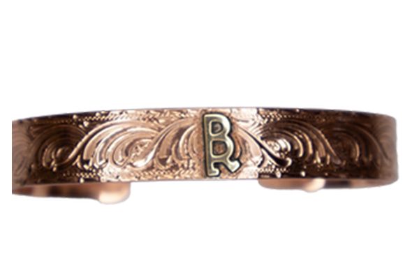 A close up of a copper bracelet with a letter b on it on a white background.
