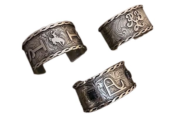 Three silver bracelets are sitting on a white surface.