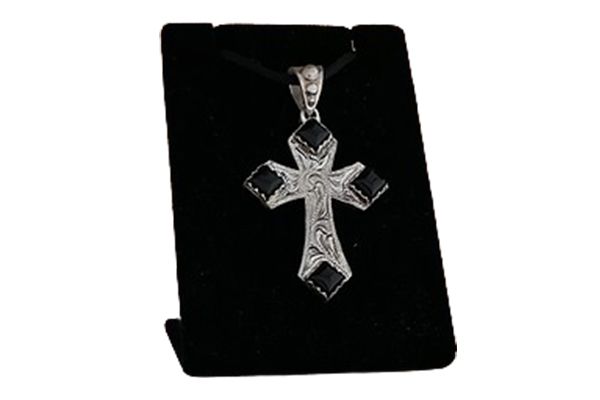 A silver cross necklace is sitting on a black velvet display case.