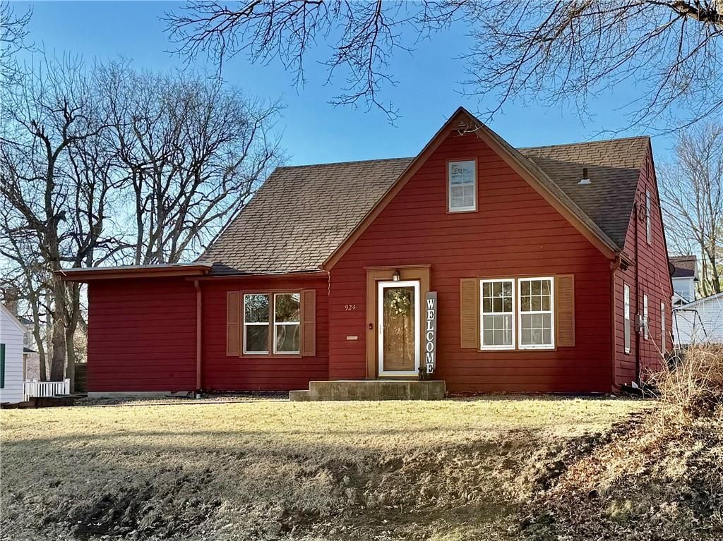 A red, single-story house with a peaked roof and a front porch, set against a clear blue sky on a sunny day.