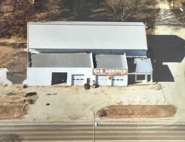 Aerial view of a small white service building with a beige lot and roadside frontage