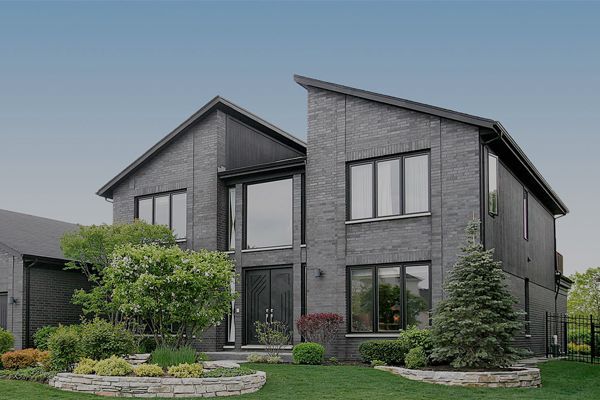 A large brick house with a lot of windows and trees in front of it.