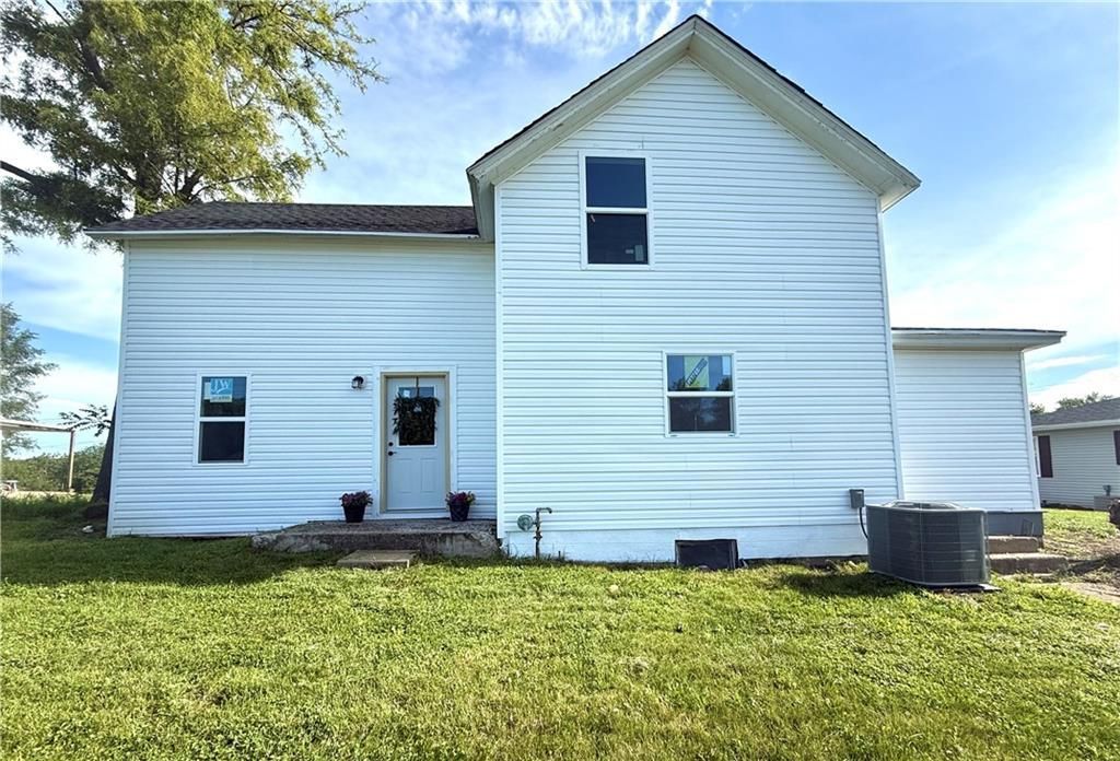 White, two-story house with white siding and windows, set on a grassy lawn.