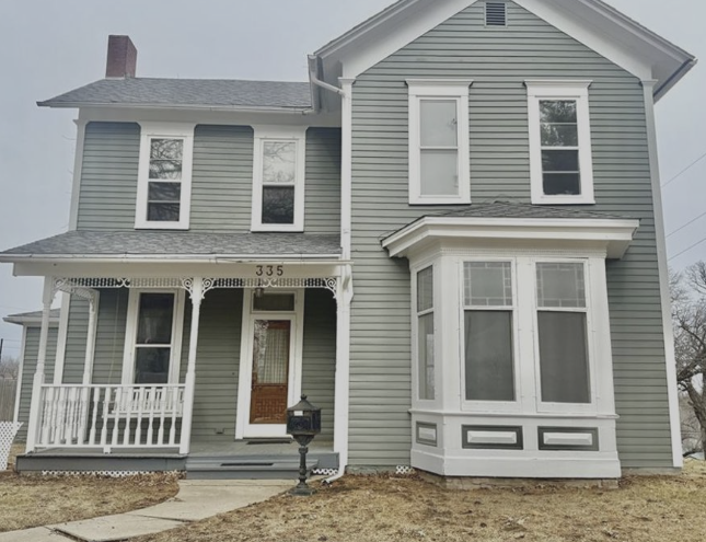 White ranch-style house with black shutters, steps to the front door, and green lawn.