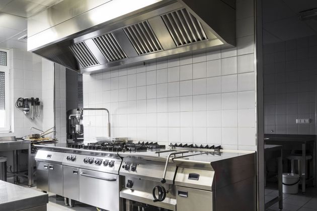 Modern commercial kitchen with stainless steel stove and large ventilation hood
