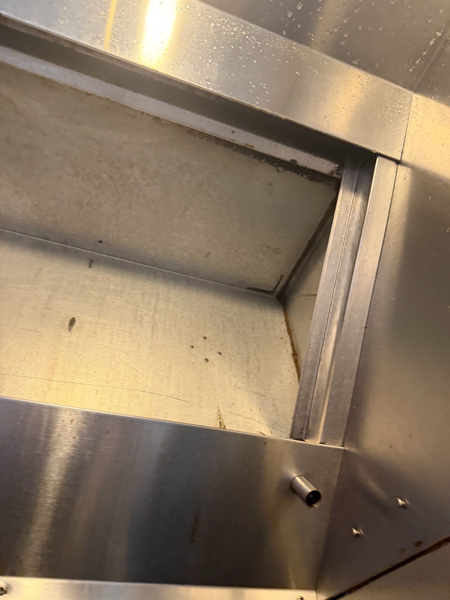 Metallic interior of an empty industrial cabinet with riveted seams and a brushed steel surface