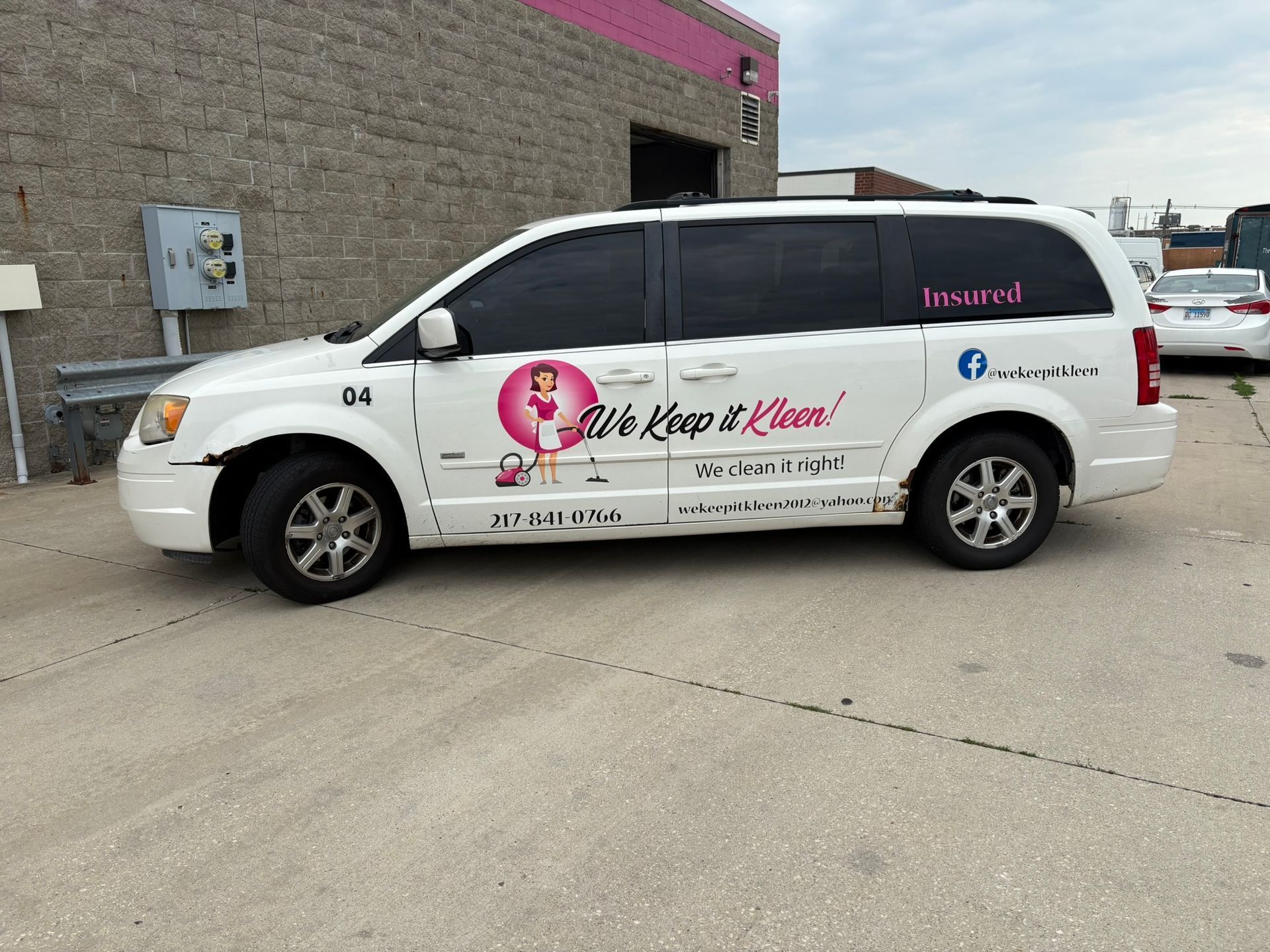 White service van with pink floral logo and text parked outside a brick building.