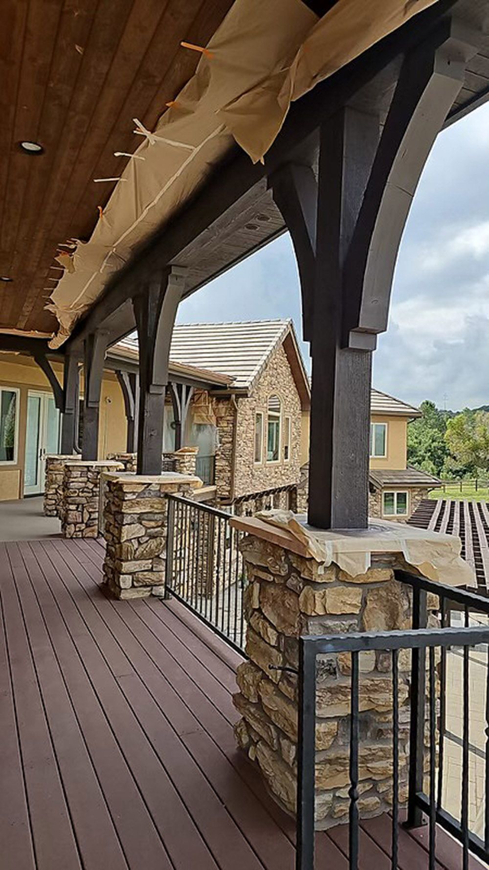 a large porch with a stone wall and a metal railing.