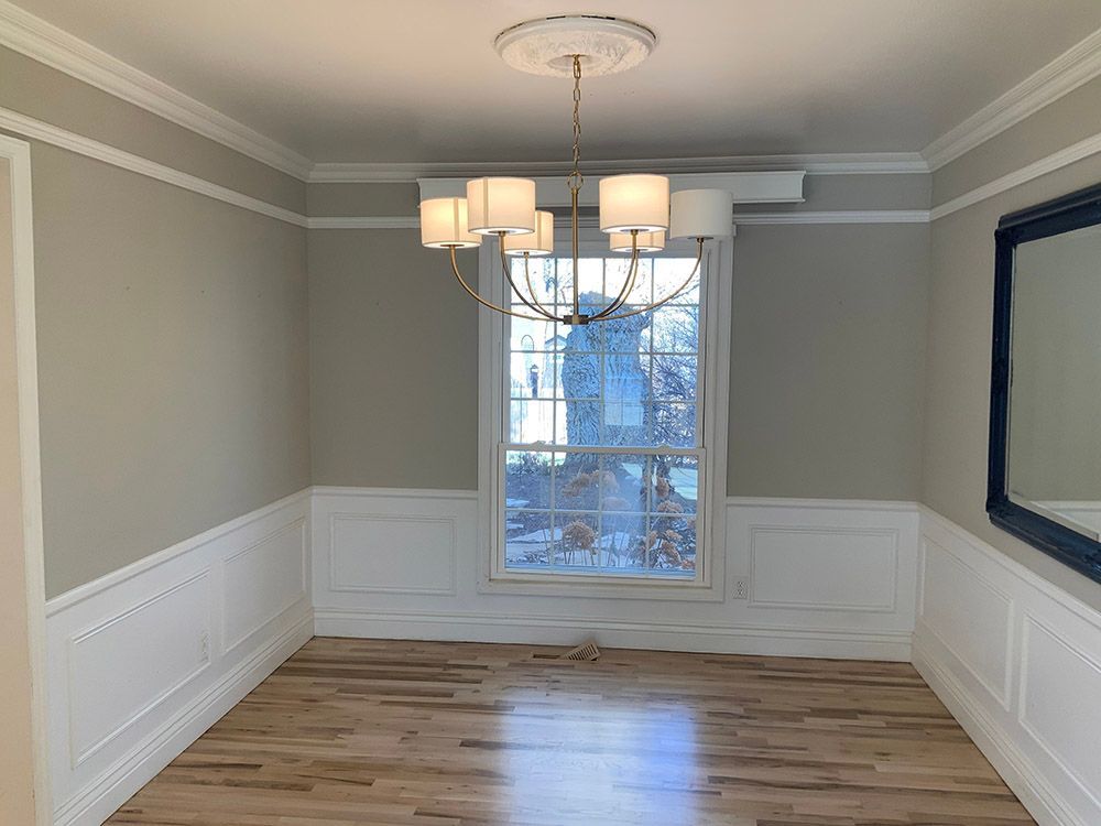 an empty dining room with a chandelier and a mirror.