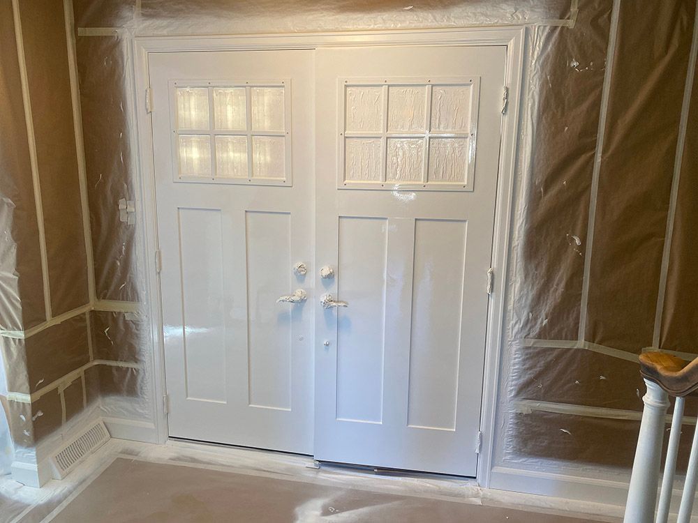 a white door is covered in plastic while being painted.
