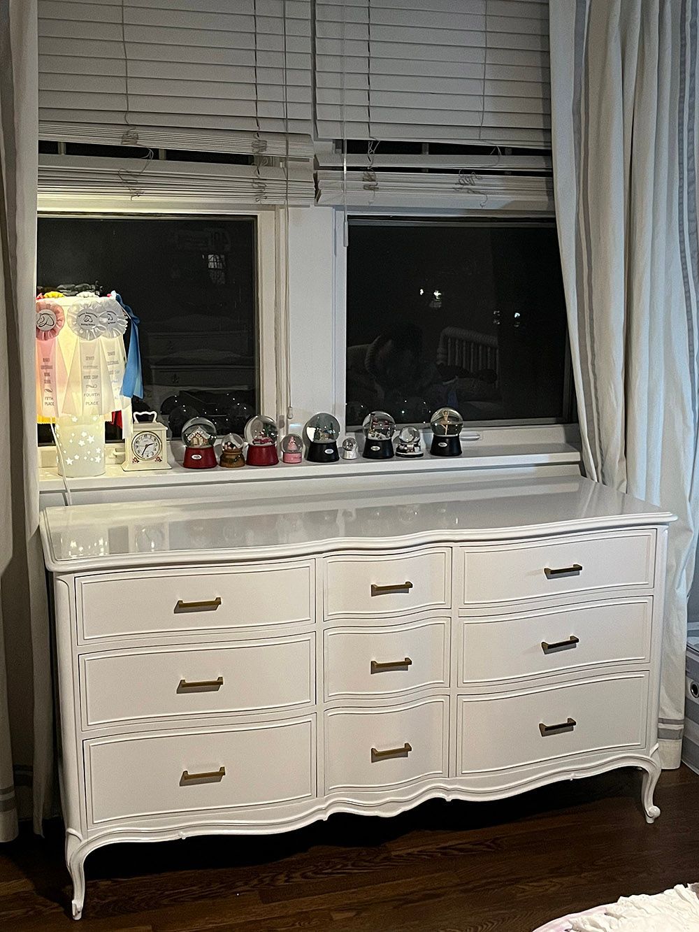 a white dresser is sitting in front of a window in a living room.