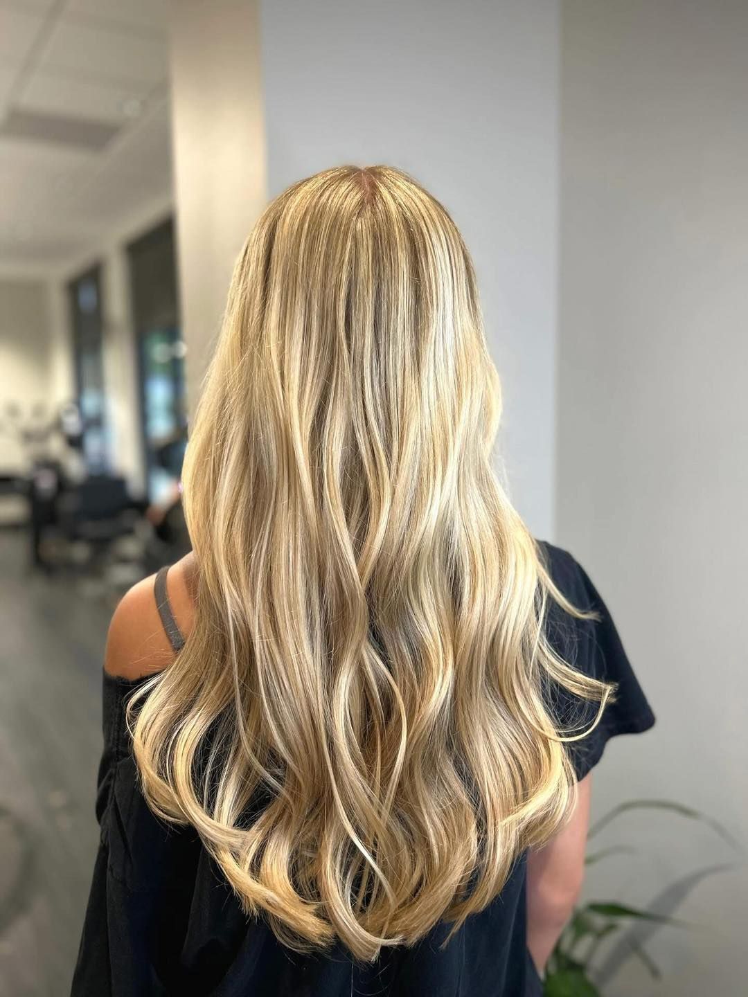 Blonde wavy hair cascades down a person's back, a salon setting.