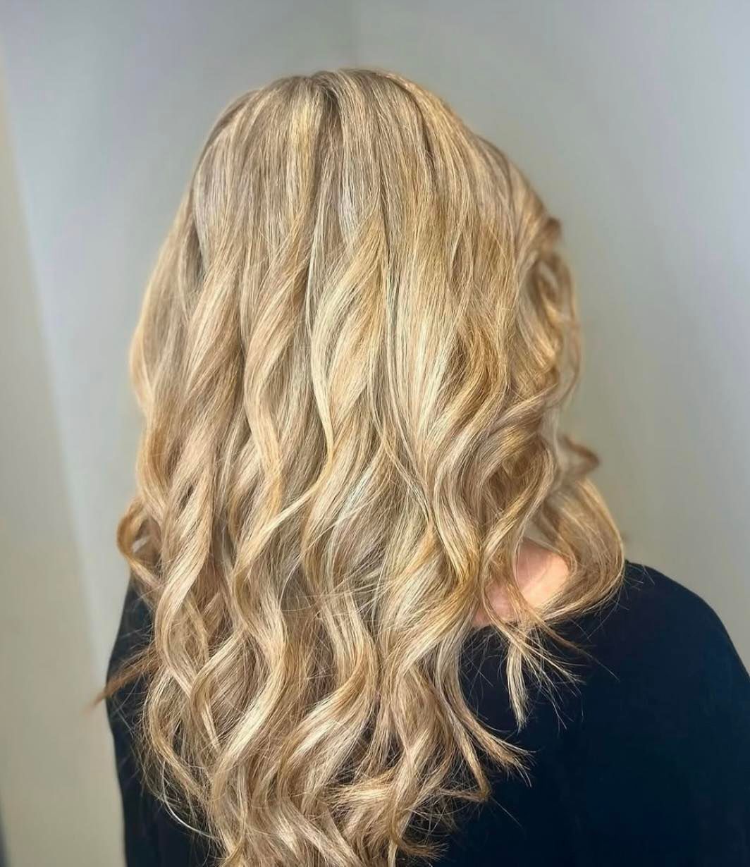 Blonde hair styled in loose waves; highlights and lowlights, with a dark top.