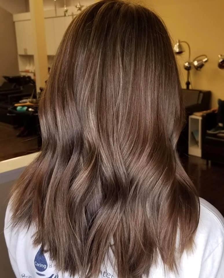 Woman with long brown hair, styled with highlights and loose waves.