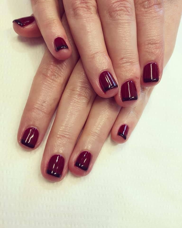 Hands with short, square burgundy nails, each outlined with a thin black border.