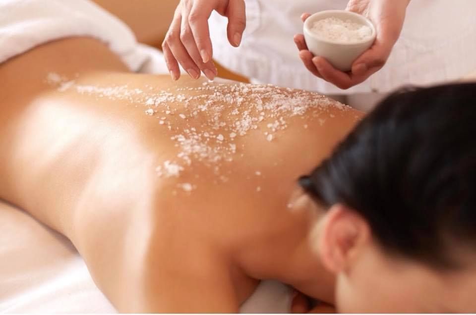 Person receiving a back scrub at a spa; salt being applied to back.